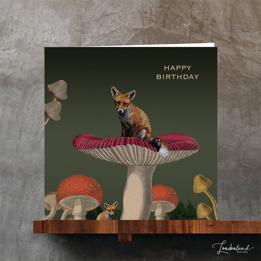 Birthday card with a fox on a mushroom with toadstools on a green background