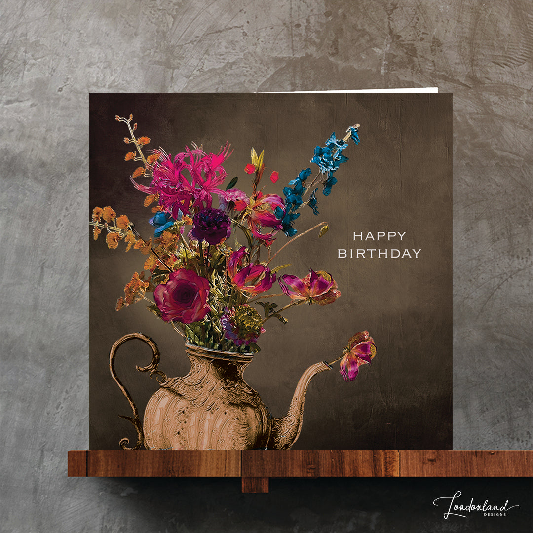 Bronze teapot vase holding a bunch of flowers and 'Happy Birthday' text on a dark background. Designer birthday card.