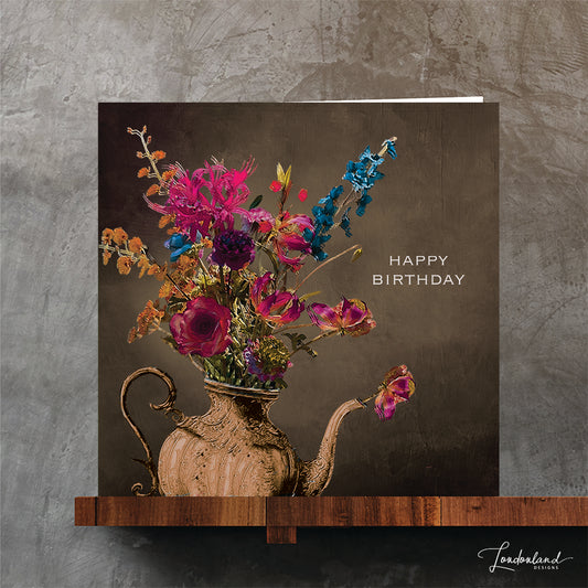 Bronze teapot vase holding a bunch of flowers and 'Happy Birthday' text on a dark background. Designer birthday card.