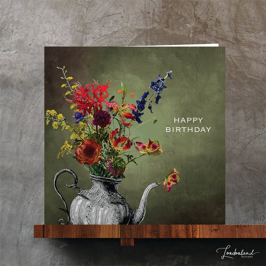 Silver teapot vase holding a bunch of flowers and 'Happy Birthday' text on a green background. Designer birthday card.