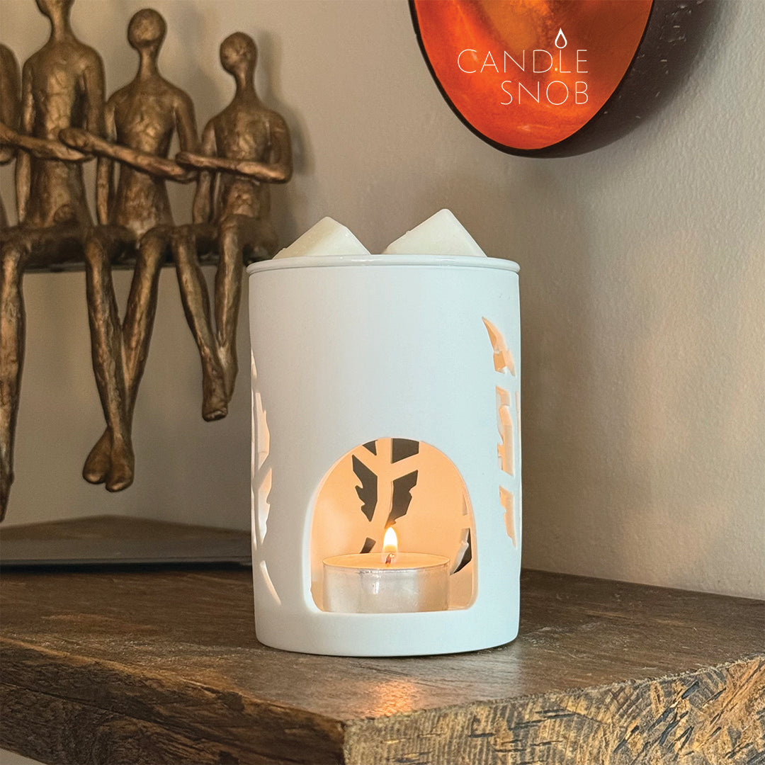White wax warmer with decorative feather design on a wooden shelf