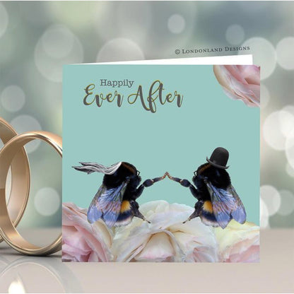 Wedding card with two bees holding hands, 'Happily Ever After' text, and wedding rings.